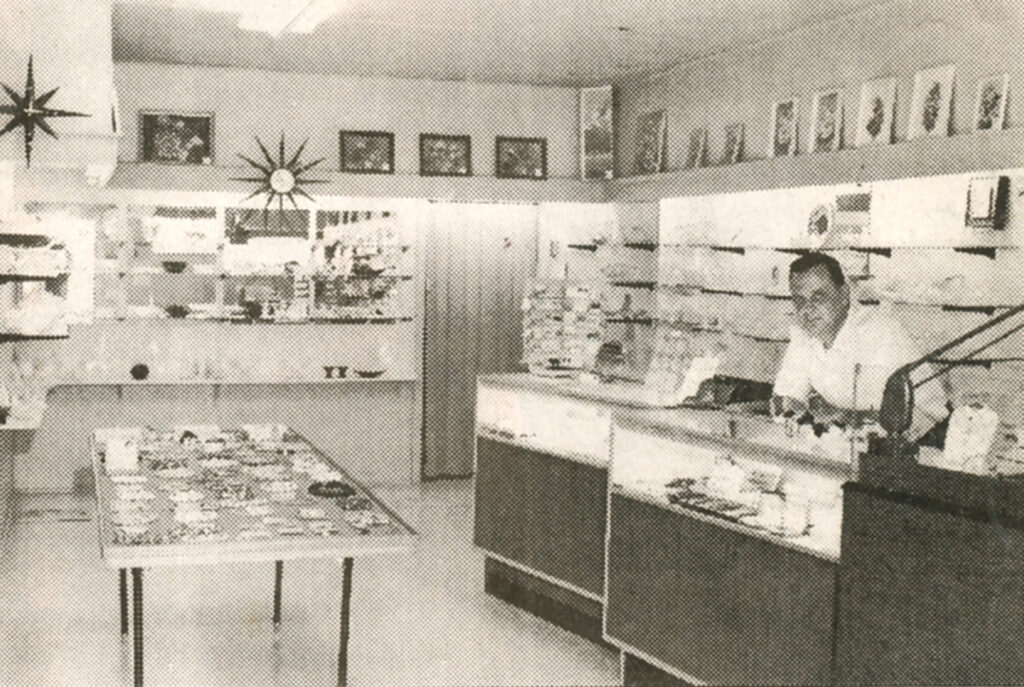 Miller's Jewelry founder Lee Miller standing at counter in store.